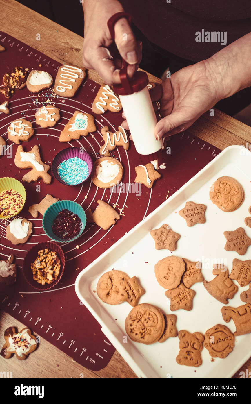 Baking Christmas cookies. Christmas gingerbread cookies in many shapes decorated with colorful frosting, sprinkle, icing, chocolate coating, toppers,  Stock Photo