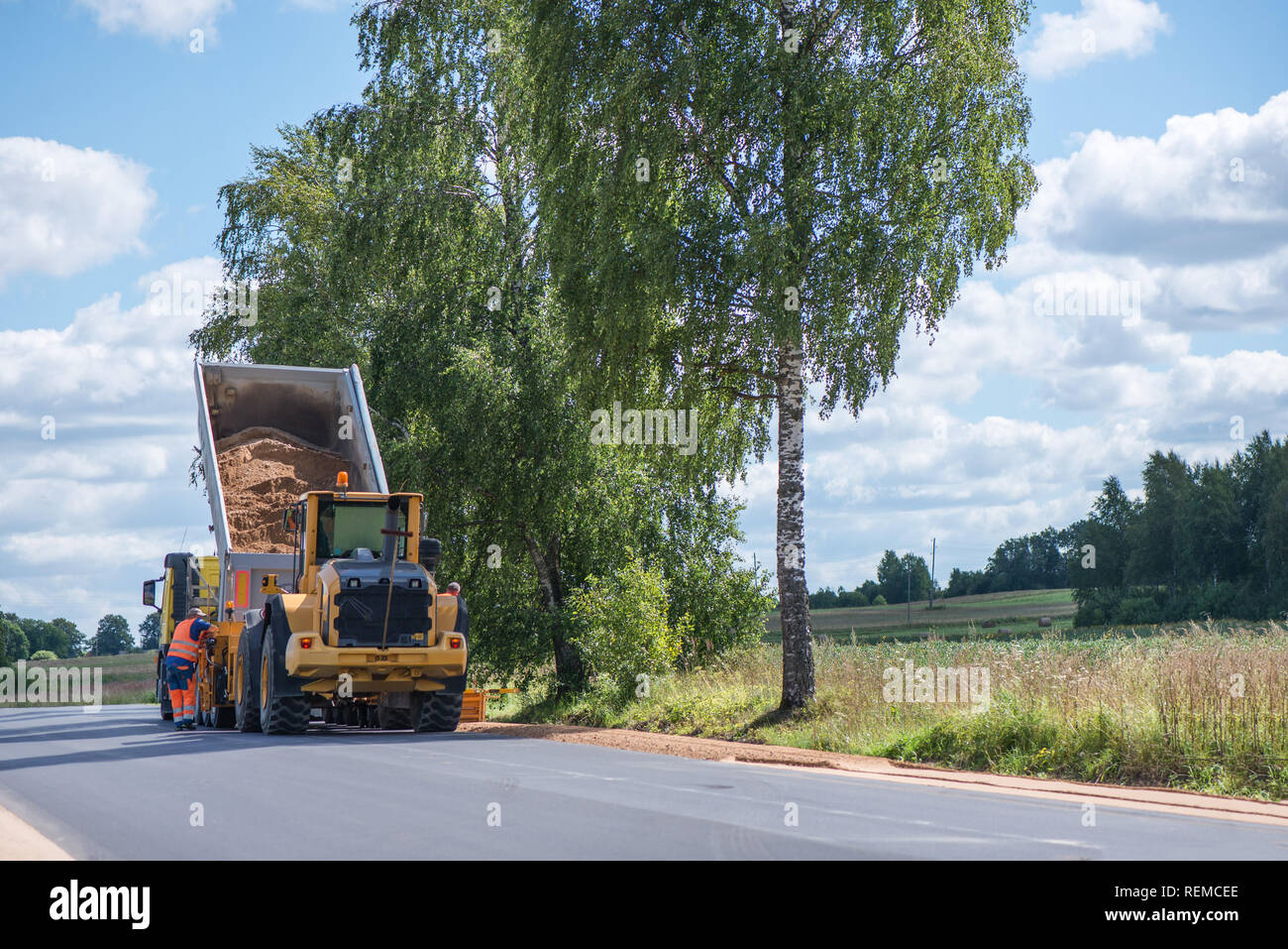Road Construction Workers Repairing Highway Road On Sunny Summer Day Loaders And Trucks Heavy Vibration Roller Compactor With Arrow Road Sign On New Stock Photo Alamy