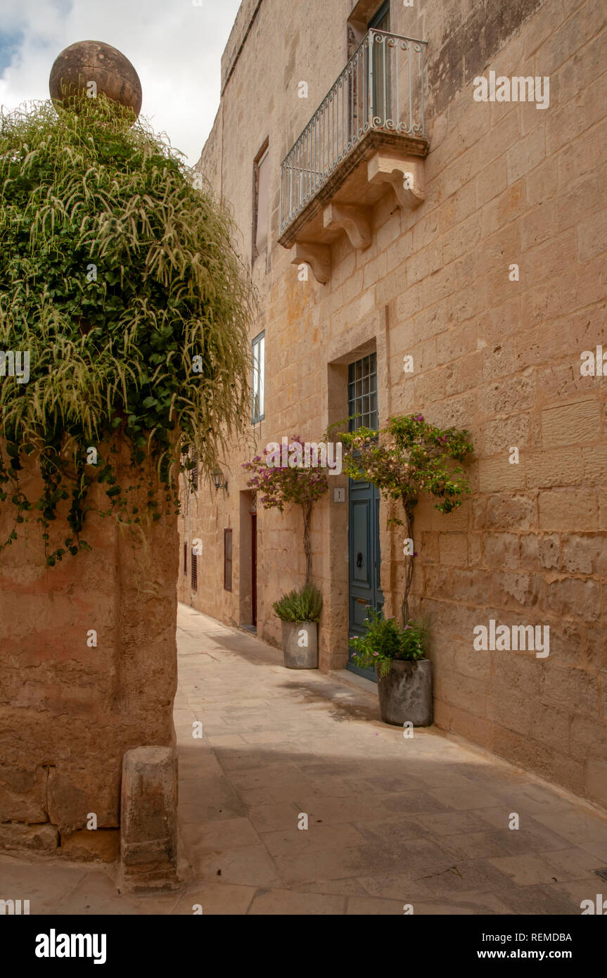 Typical narrow streets between limestone houses in the ancient, walled city of Mdina in Malta. Here on the corner of Gatto Murina Street and Mesquita  Stock Photo