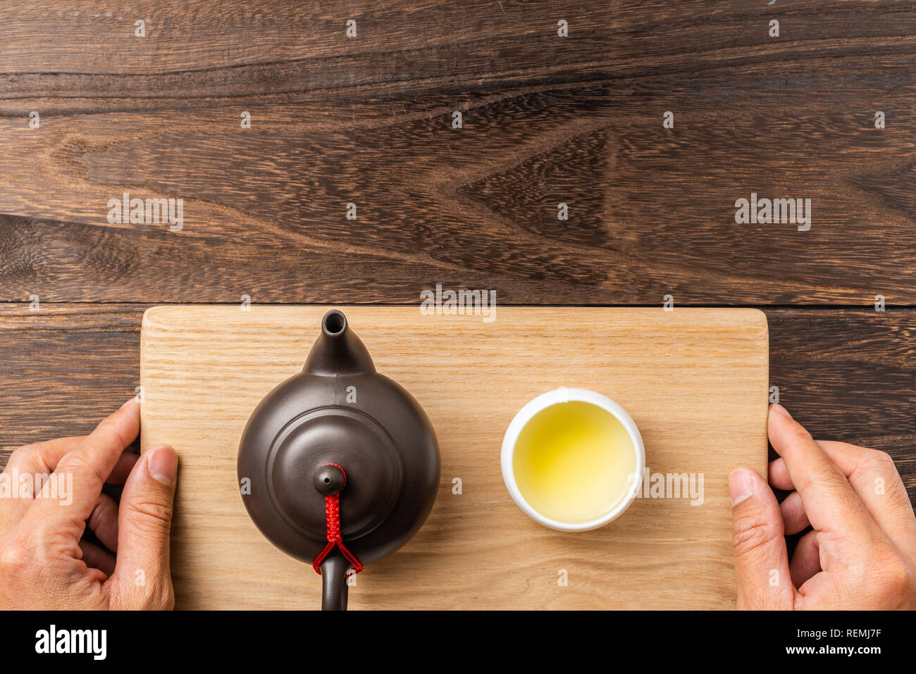 Asia culture and design concept - man's hand hold fresh taiwan oolong tea and teapot on dark wood background Stock Photo