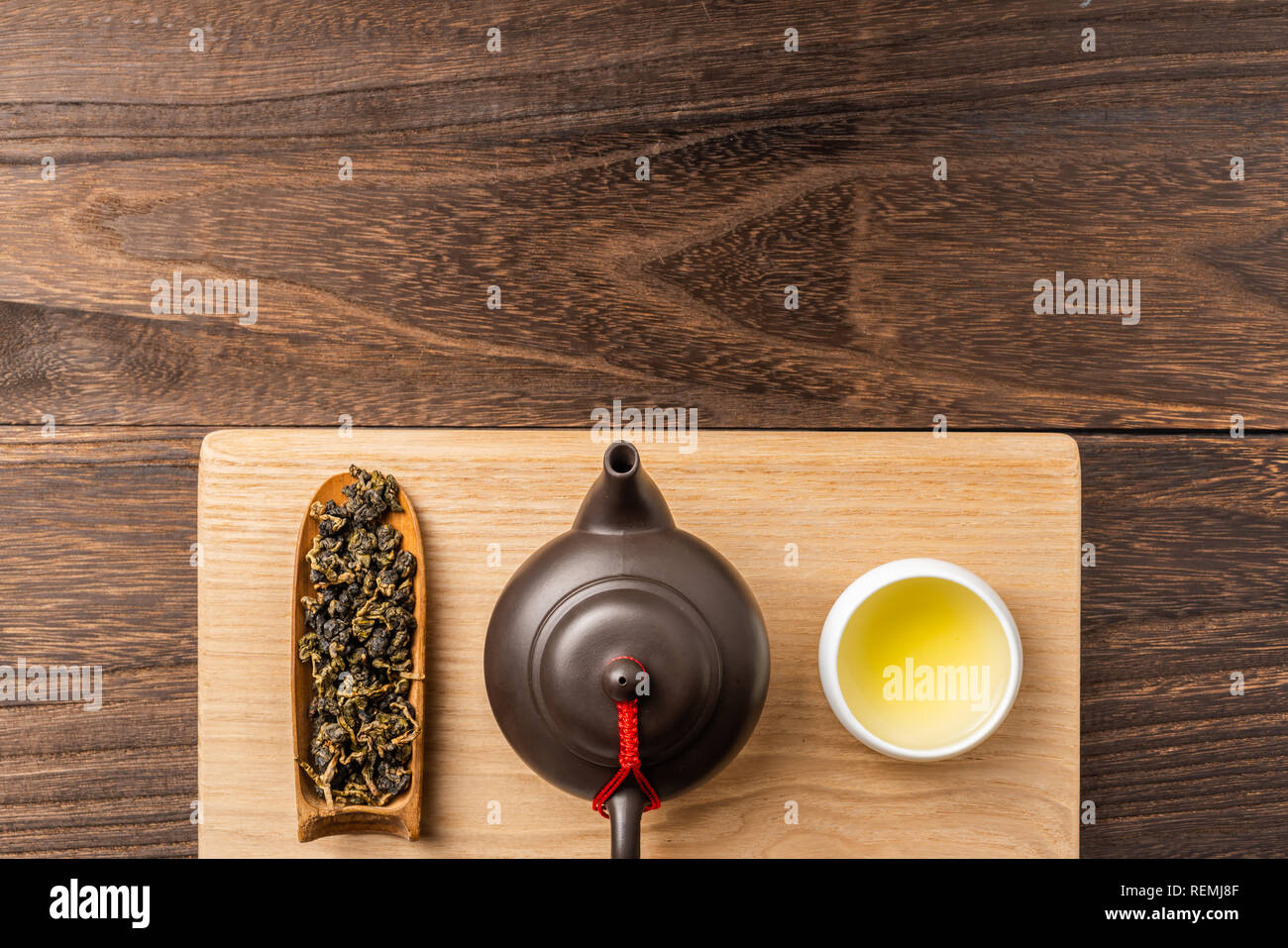 Asia culture and design concept - man's hand hold fresh taiwan oolong tea and teapot on dark wood background Stock Photo