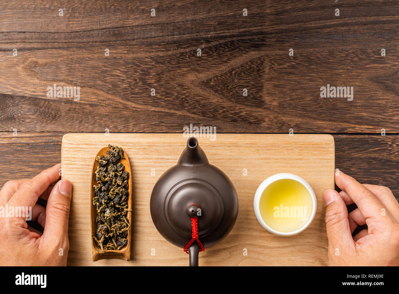 Asia culture and design concept - man's hand hold fresh taiwan oolong tea and teapot on dark wood background Stock Photo
