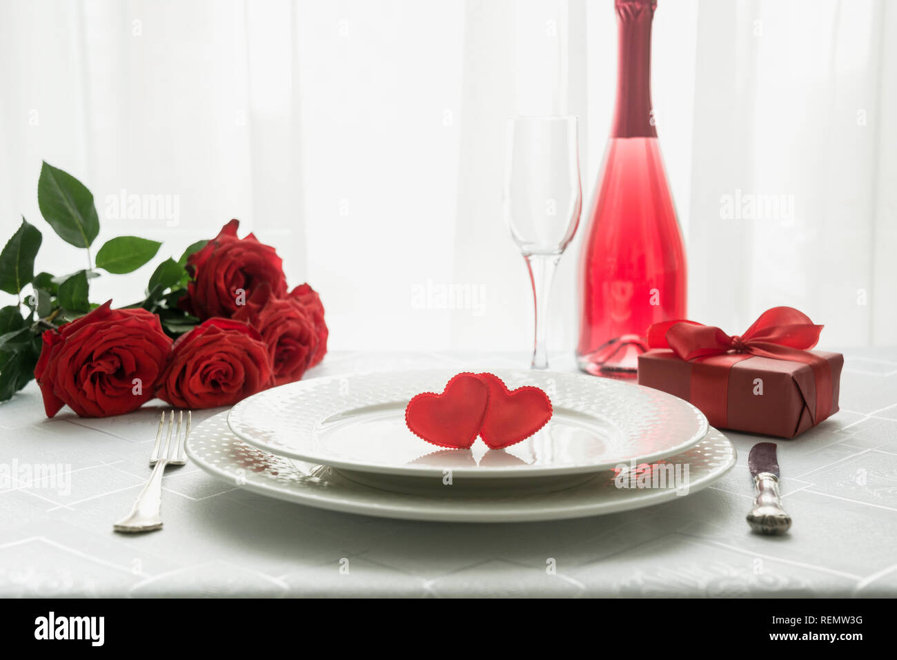 Valentines day table place setting with red roses and champagne. Space ...