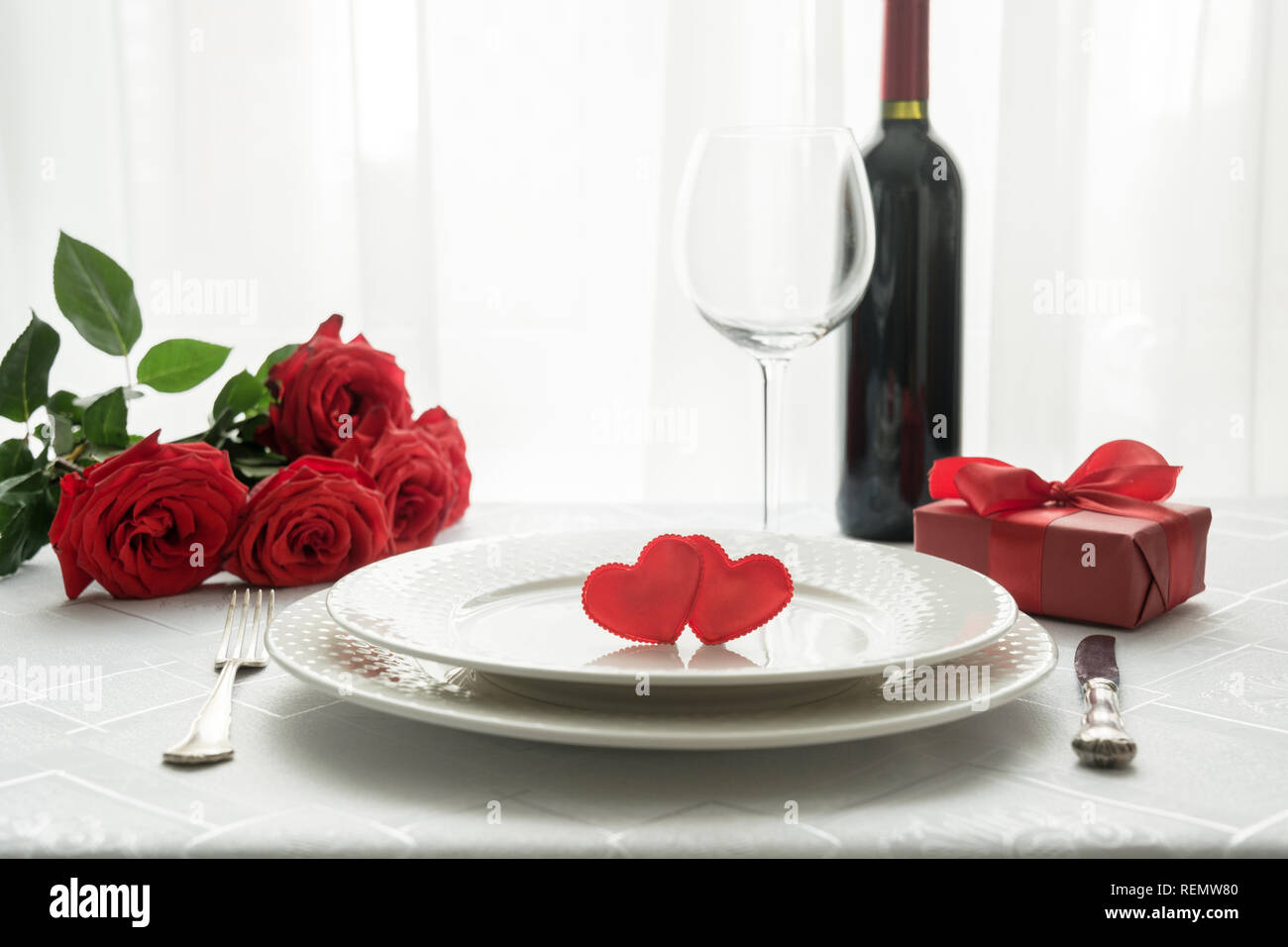 Valentines day table place setting with red roses, gift box, and wine ...