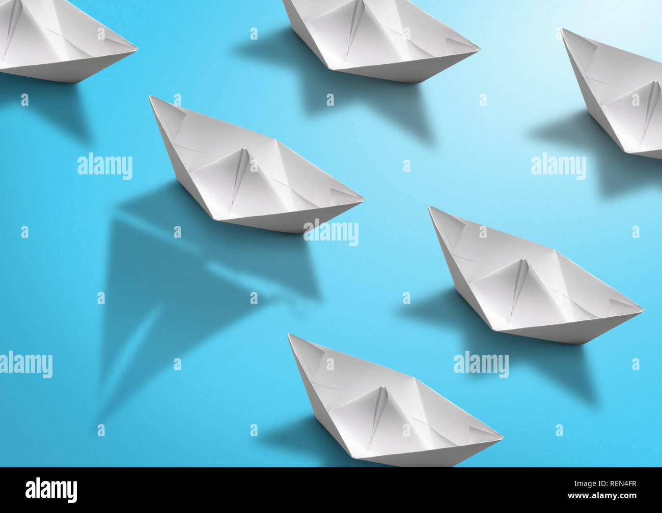 stand out concept, paper ship with sailing boat shadow on blue Stock Photo