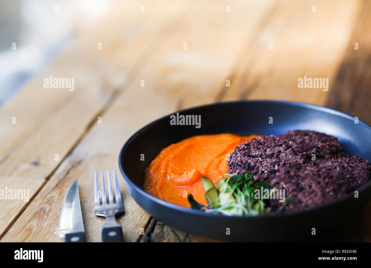 Vegan black rice cutlets served with orange carrots mesh and microgreeens. Vegeterian food hipster cafe. Space for text Stock Photo