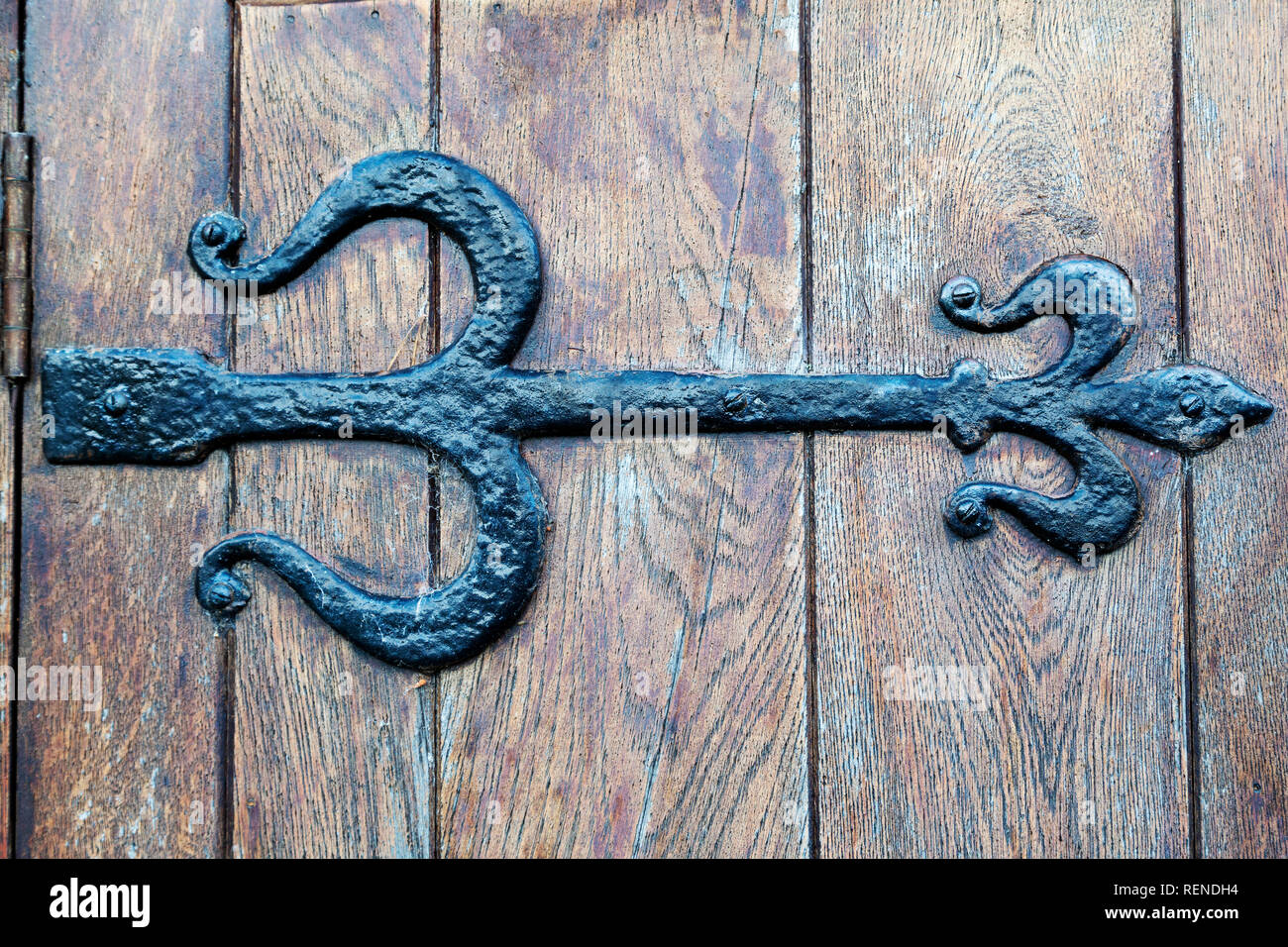 A Tudor-style cast iron door hinge. The hinge is on a wooden door. Stock Photo