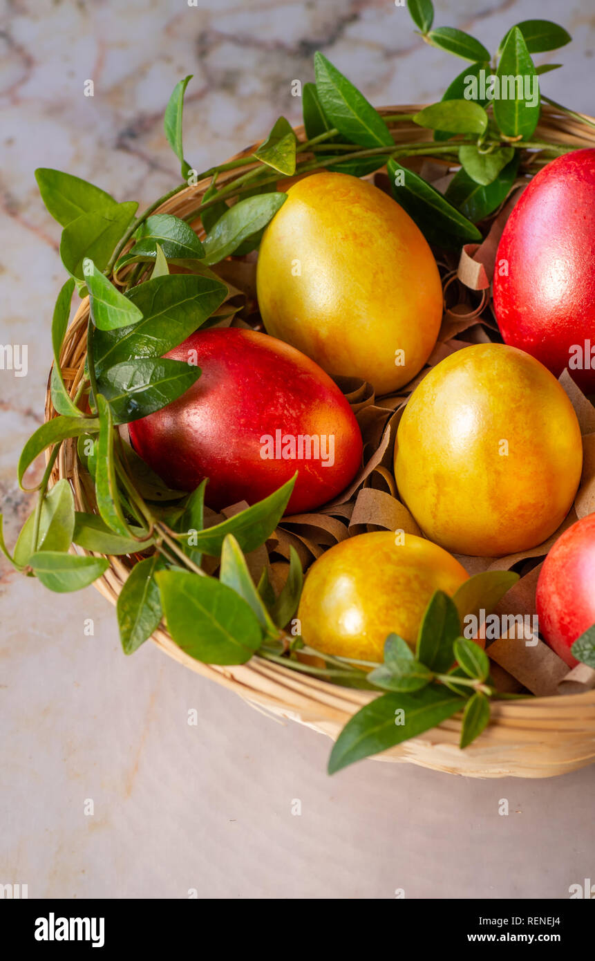 Easter eggs in the basket. Easter eggs on marble background. A sprig of greenery. Stock Photo
