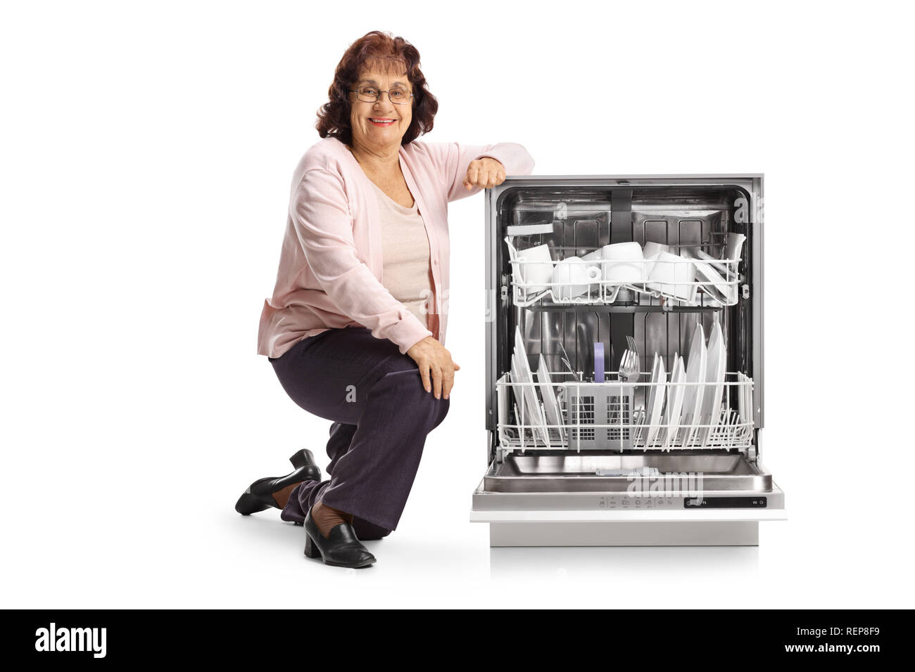 Elderly woman with an open loaded dishwasher isolated on white