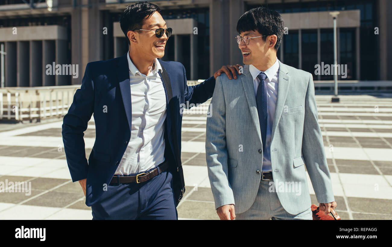 Two successful business partners walking together outdoors. Korean business men walking against office building Stock Photo Alamy