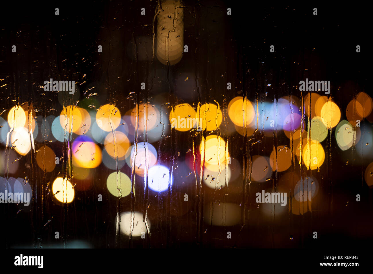 Rain drops on window with road light bokeh. City life in night in rain ...