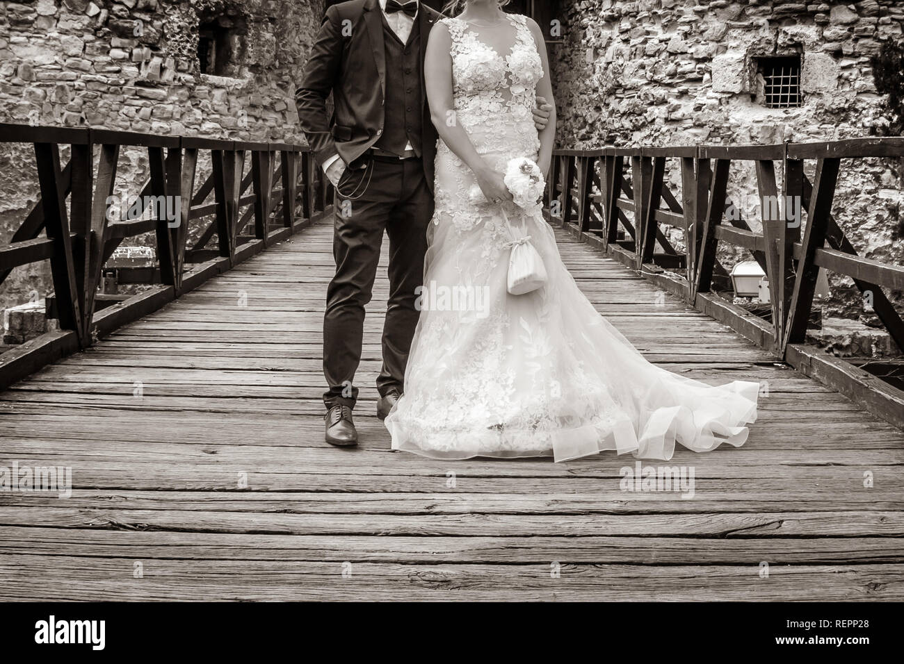 Wedding couple stand on the wooden bridge in the front of old fortress ...