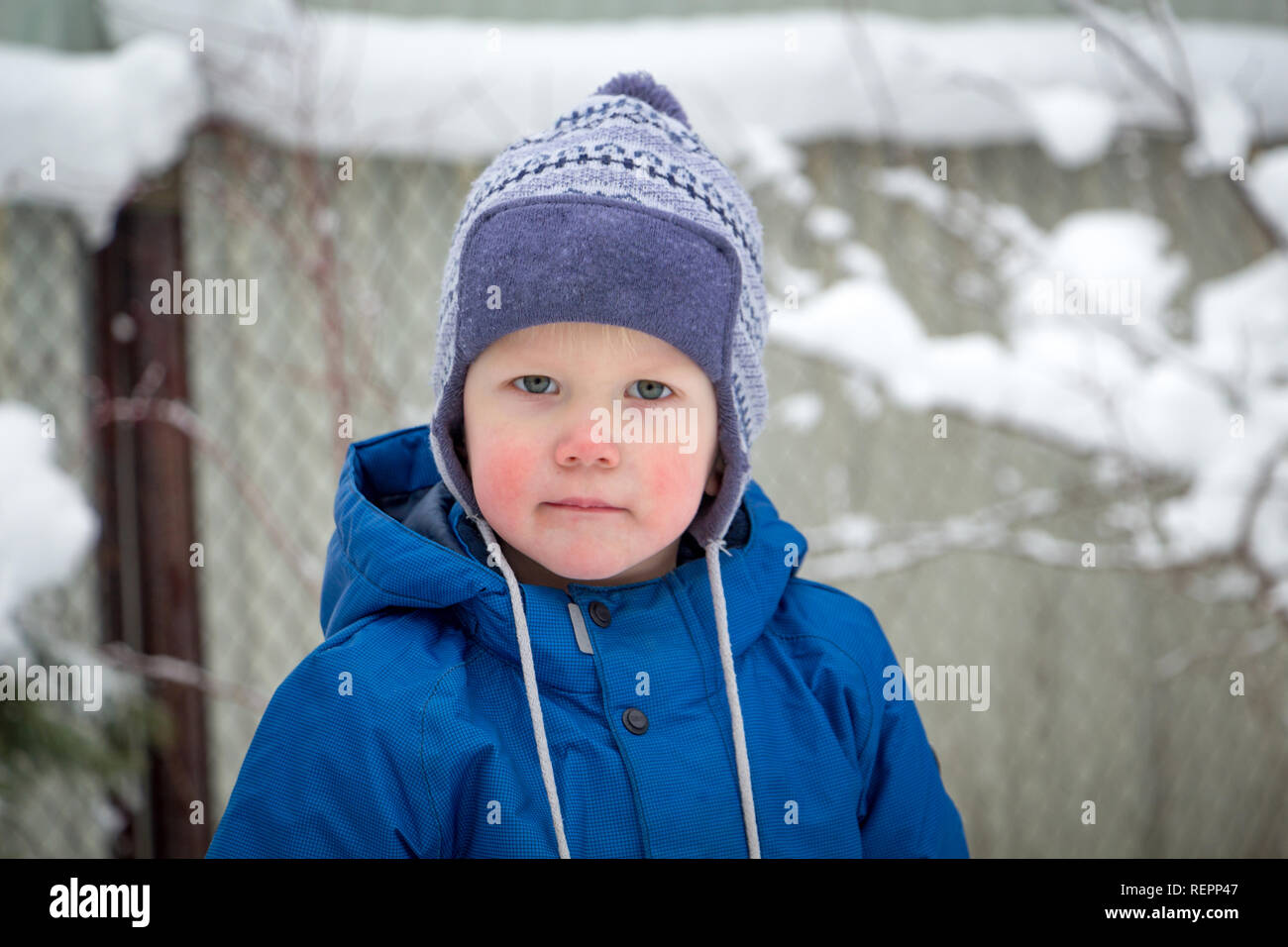 Portrait of a little boy in a winter hat and jacket while walking on a cold winter snowy day Stock Photo
