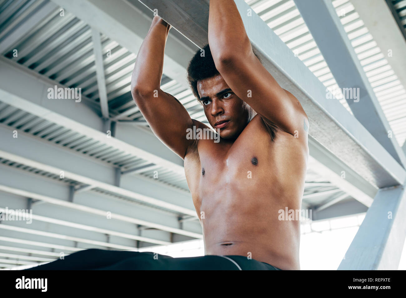 Athletic man doing pull ups during an outdoor workout Stock Photo