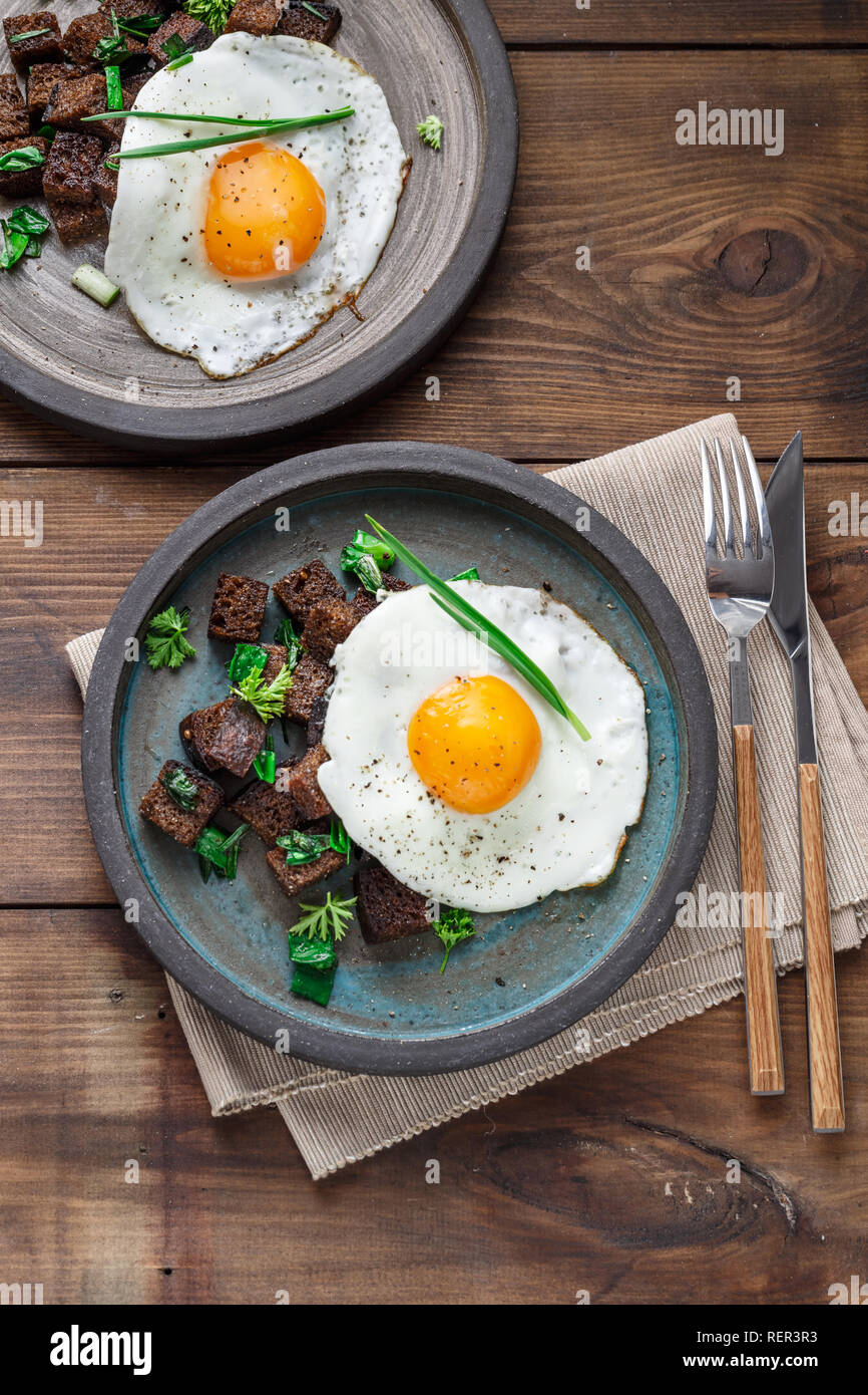 Sunny side fried egg with croutons and herbs, close view Stock Photo