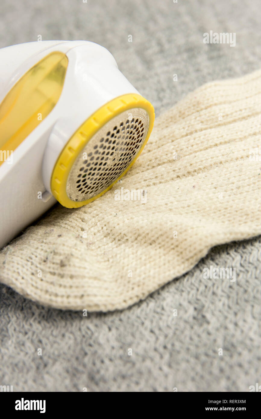 Removing sheaving lint fuzz from white woolen socks, wool clothes maintain concept. Stock Photo