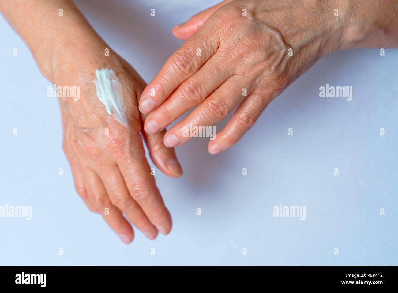 Skin care. Elderly woman applies Cream On Her Hands. Beauty product