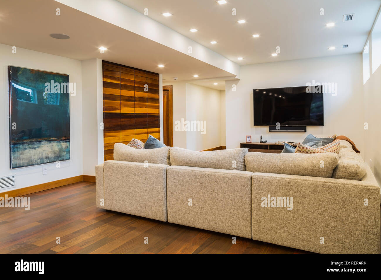 Grey upholstered sectional sofas in illuminated white basement family
