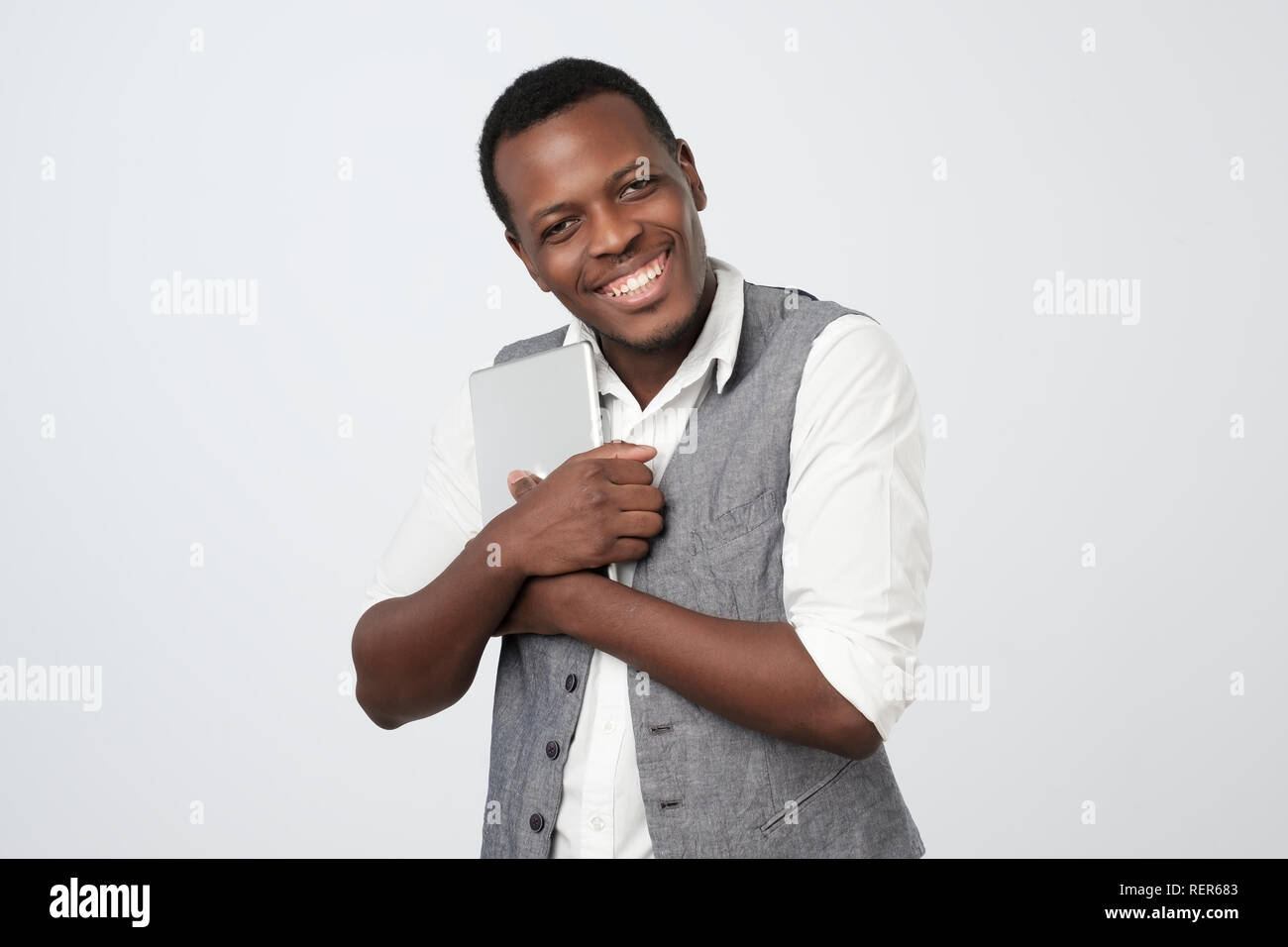 African businessman hugging his tablet with love. Stock Photo
