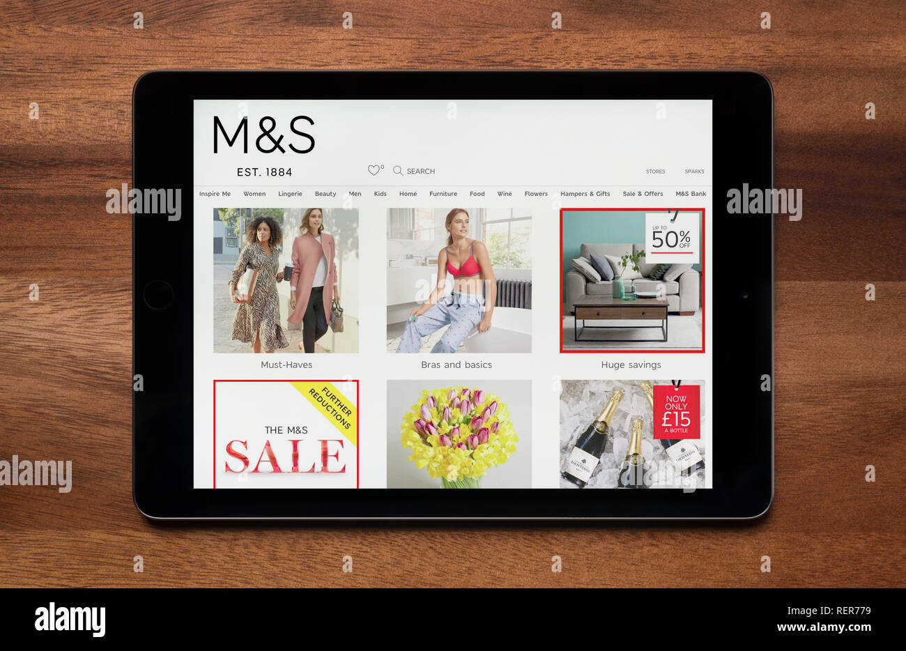 The website of Marks & Spencer is seen on an iPad tablet, which is resting on a wooden table (Editorial use only). Stock Photo