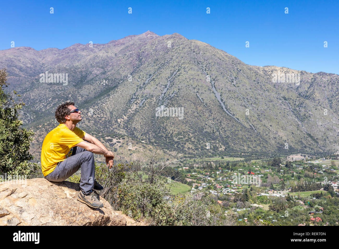 One man hiker with sunglasses looking at landscape views inside a valley at Andes mountains. An amazing rugged scenery on a sunny day Stock Photo