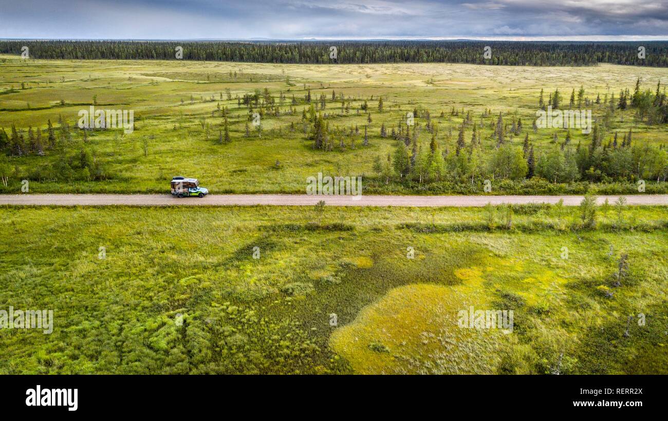 Drone view, aerial photo, motorhome (Ford Ranger with body Oman) on gravel road in wetland, bog with boreal, arctic conifers Stock Photo