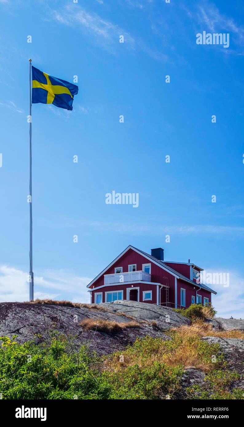 Red wooden house, next to the Swedish flag, Vinga, Sweden Stock Photo