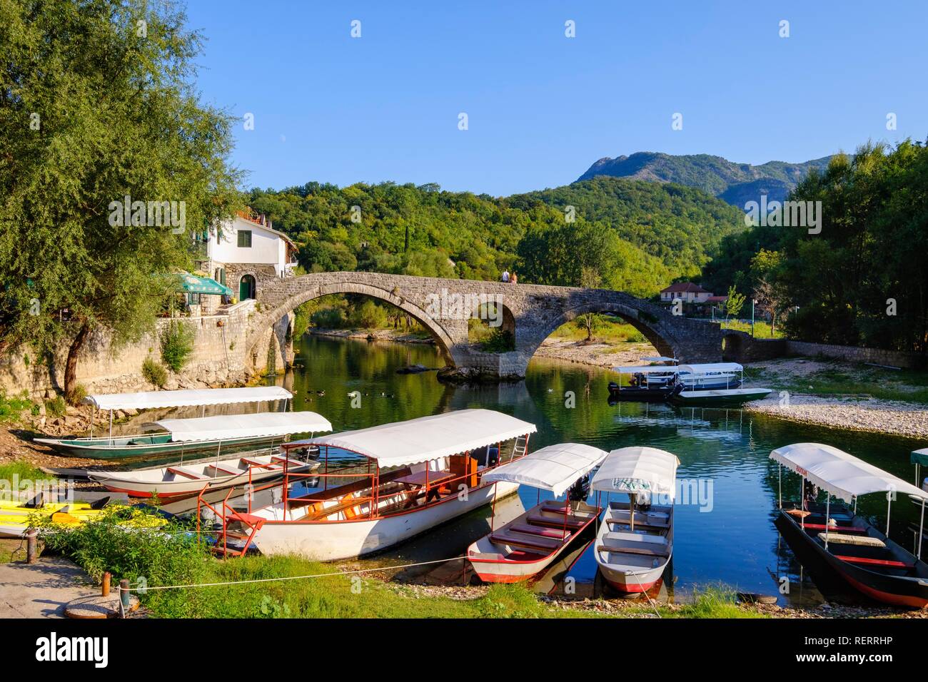 Excursion boats and Old Bridge Stari most, river Crnojevic, Rijeka Crnojevica, national park Lake Skadar, near Cetinje Stock Photo