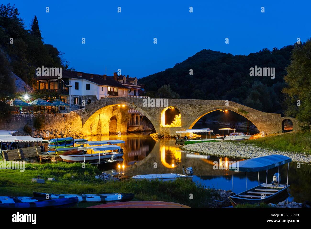 Excursion boats and Old Bridge Stari most at dusk, river Crnojevic, Rijeka Crnojevica, national park Lake Skadar Stock Photo