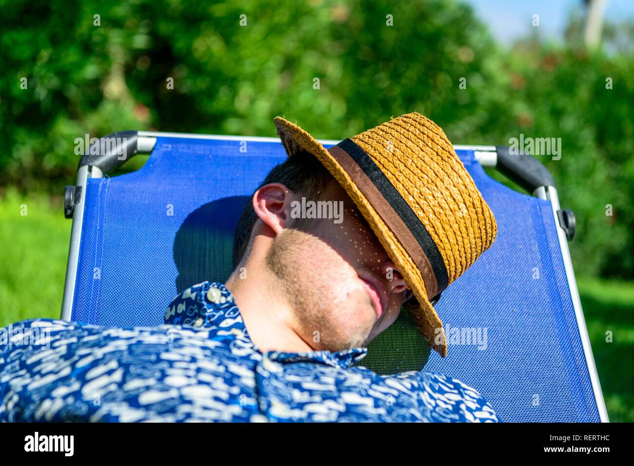 Young man with a straw hat sleeping on a sun lounger on holiday, Italy Stock Photo