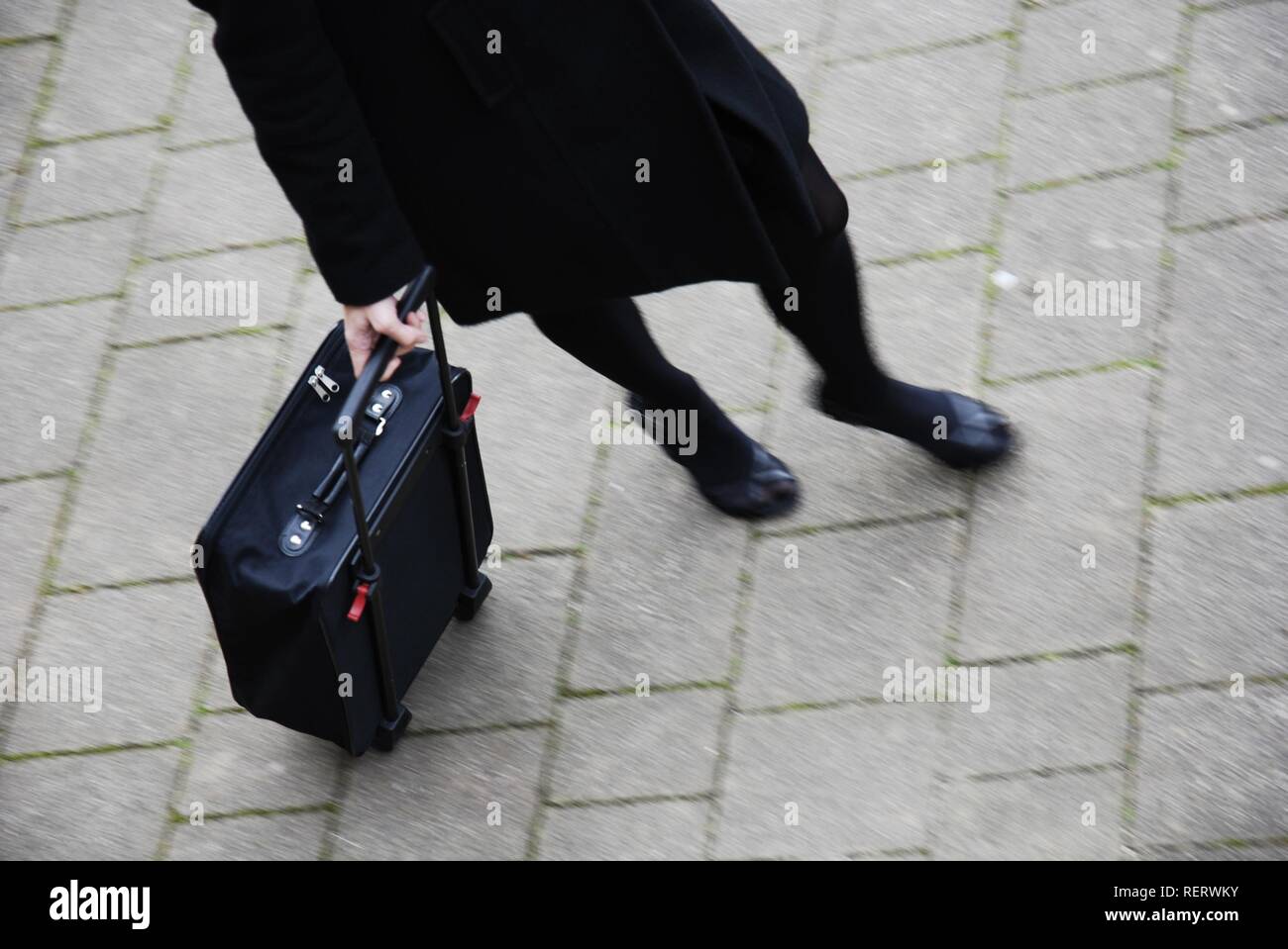 Young woman, partial view, rushing with an overnight case Stock Photo
