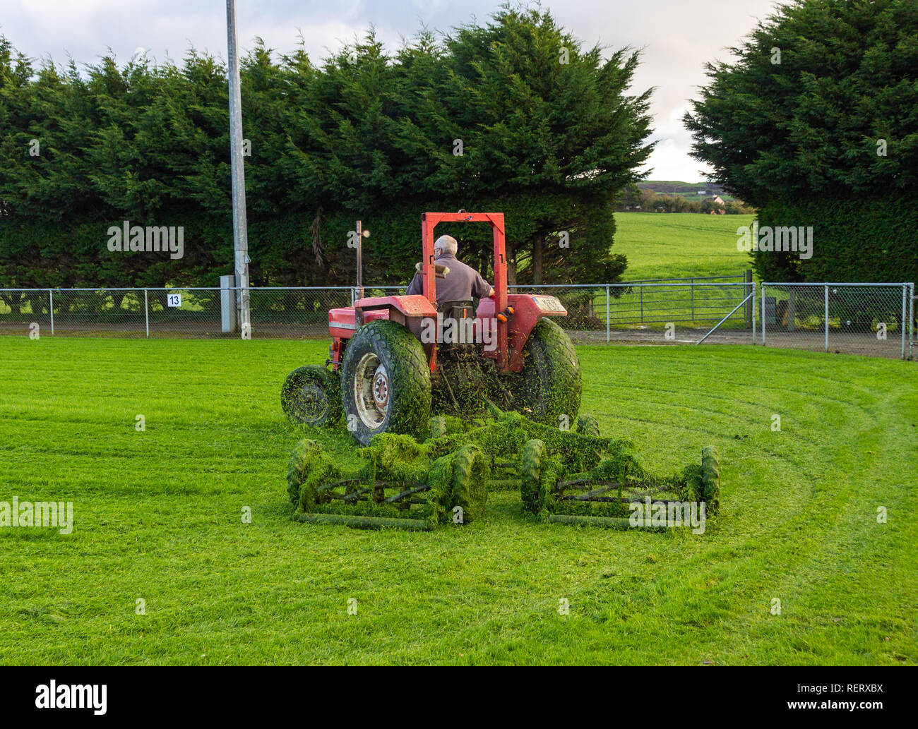 man on a tractor pulling a set of gang mowers Stock Photo