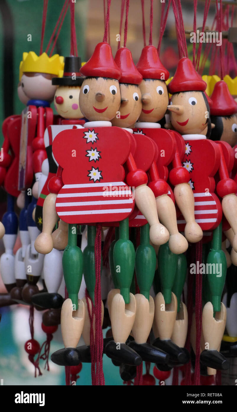 Wood Pinocchio (aka Jumping Jack) toy figurines hang from strings on a display rack in a European shop. Stock Photo