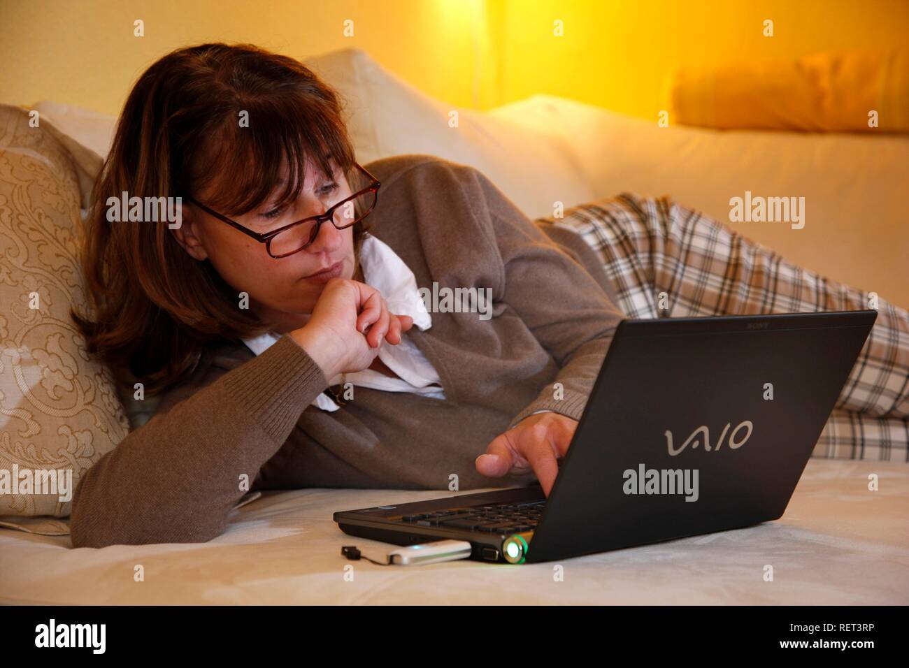 Woman, 45 years old, surfing the internet with a laptop on a sofa, DSL-stick, mobile internet Stock Photo