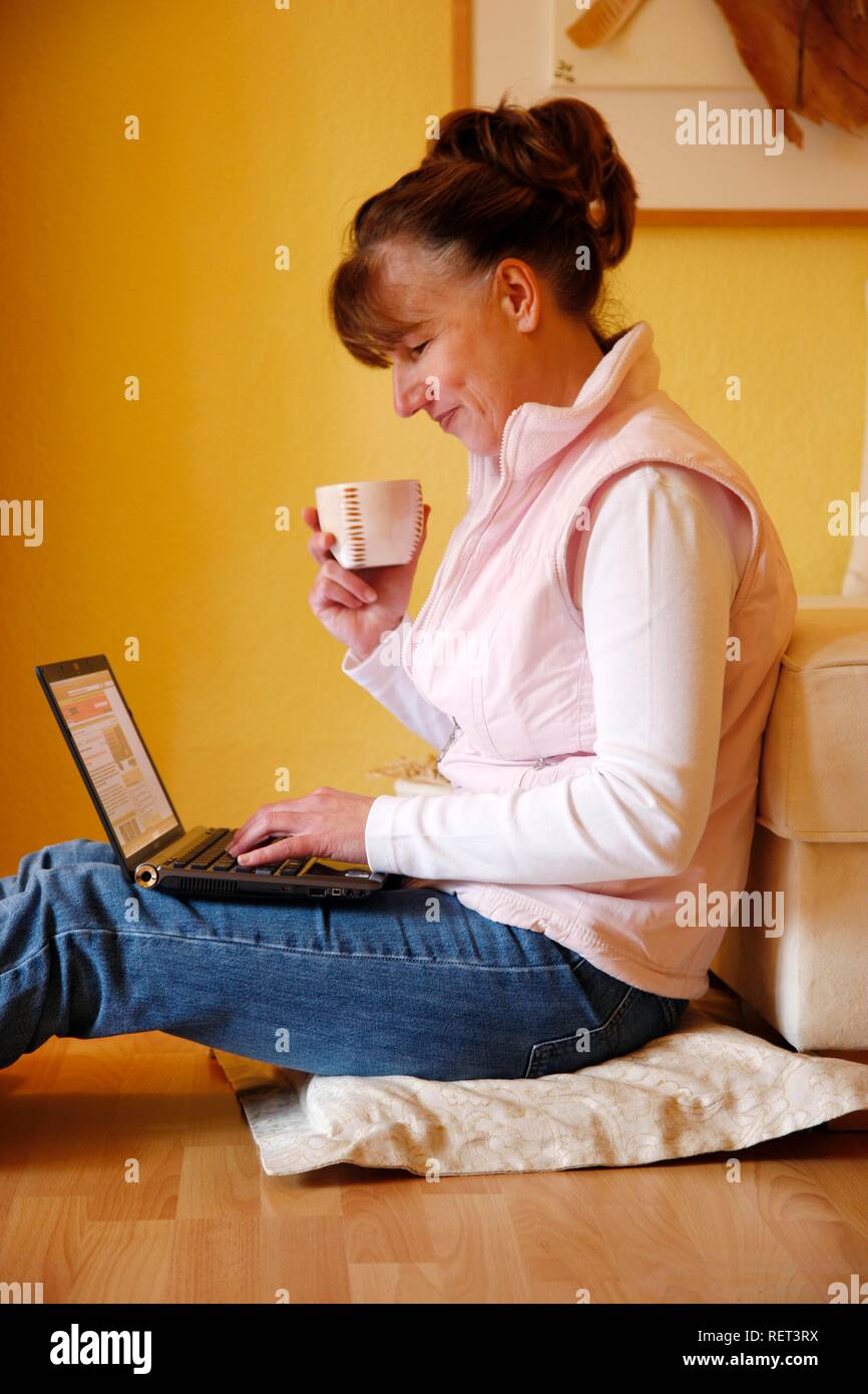 Woman, 45 years old, surfing the internet with a laptop in her flat Stock Photo