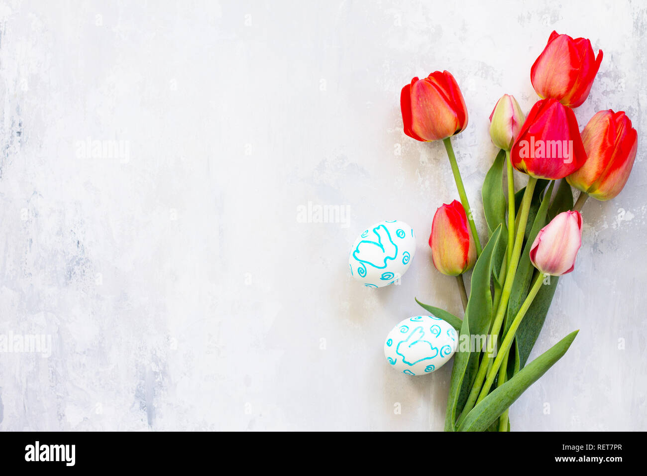 Easter table setting with tulips flowers and Easter eggs. Holidays background. Top view flat lay background. Copy space. Stock Photo
