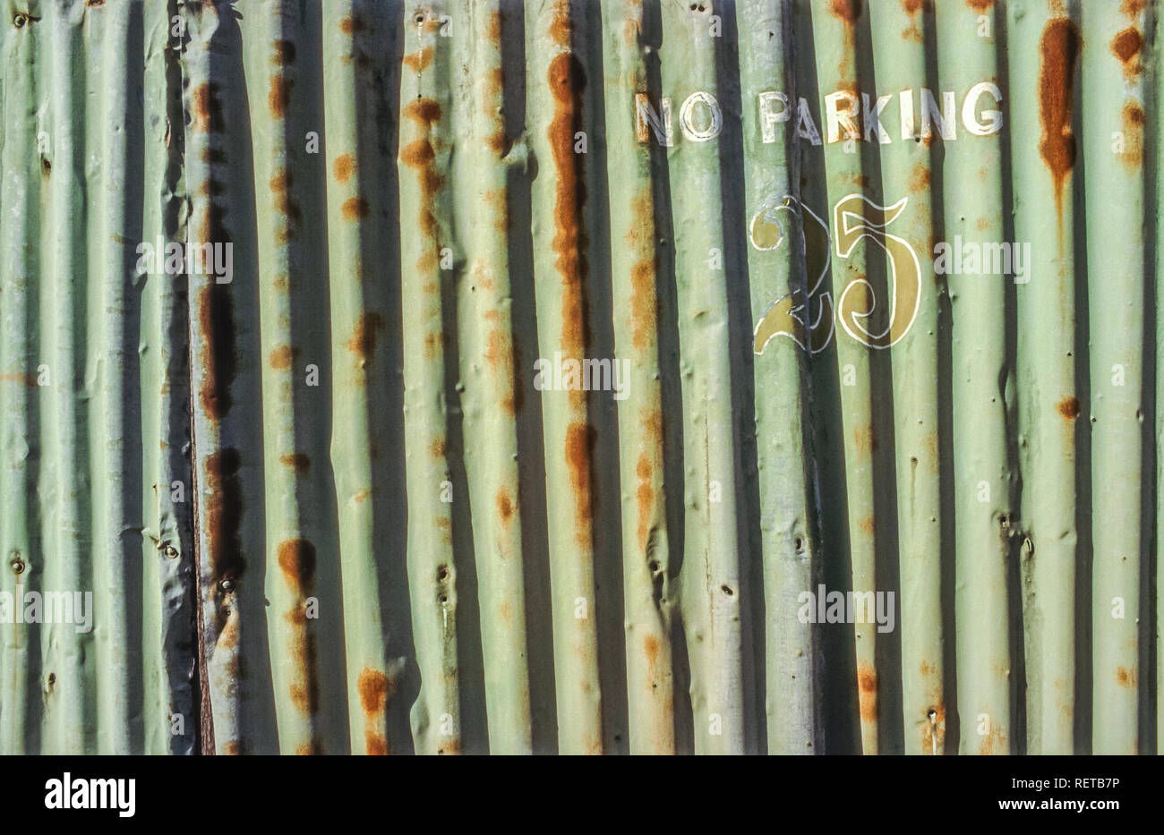 No parking and number 25 painted on a rusted corrugated sheet metal wall Stock Photo