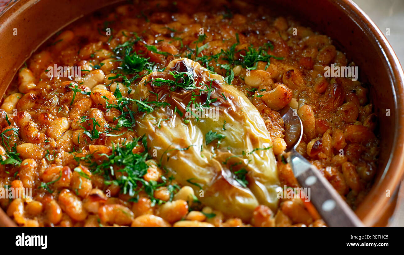 Serbian National Cuisine dish Baked Beans or Prebranac served with green paprika and parsley in a terracotta pot Stock Photo