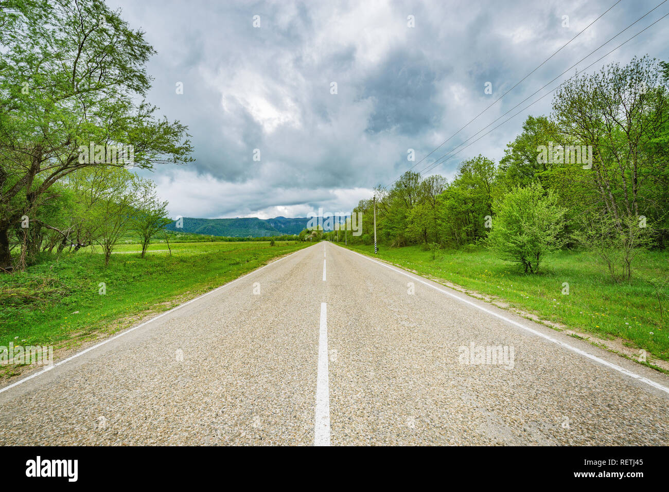 Asphalt road to the mountains under the dramatic stormy sky Stock Photo ...