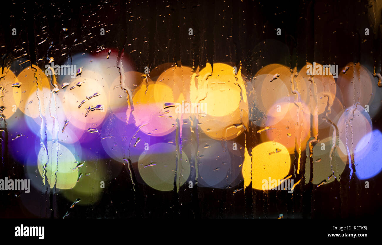 Rain drops on window with road light bokeh. City life in night in rain ...