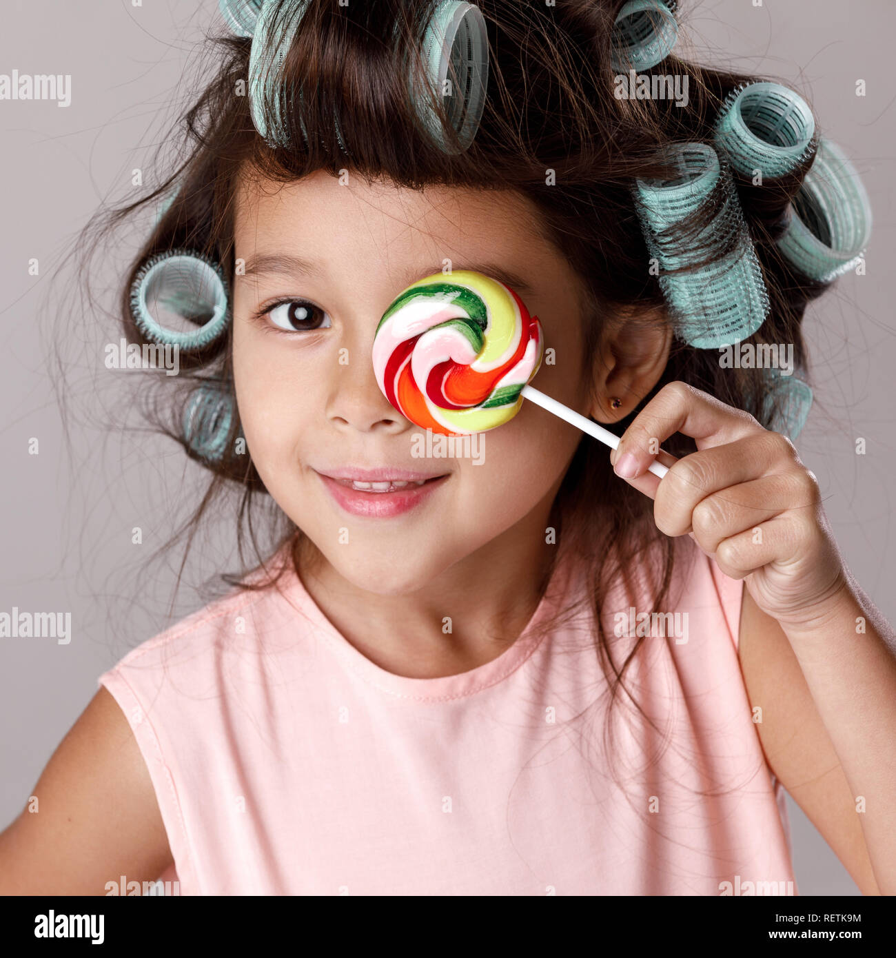 Funny Little Girl In Pink Dress And Hair Curlers Holding