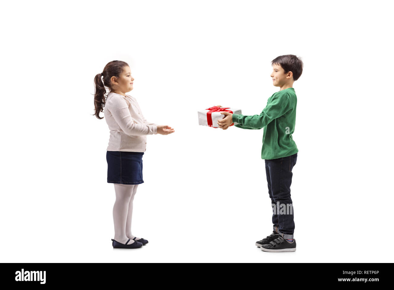 Full length profile shot of a little boy giving a present to a little girl isolated on white background Stock Photo