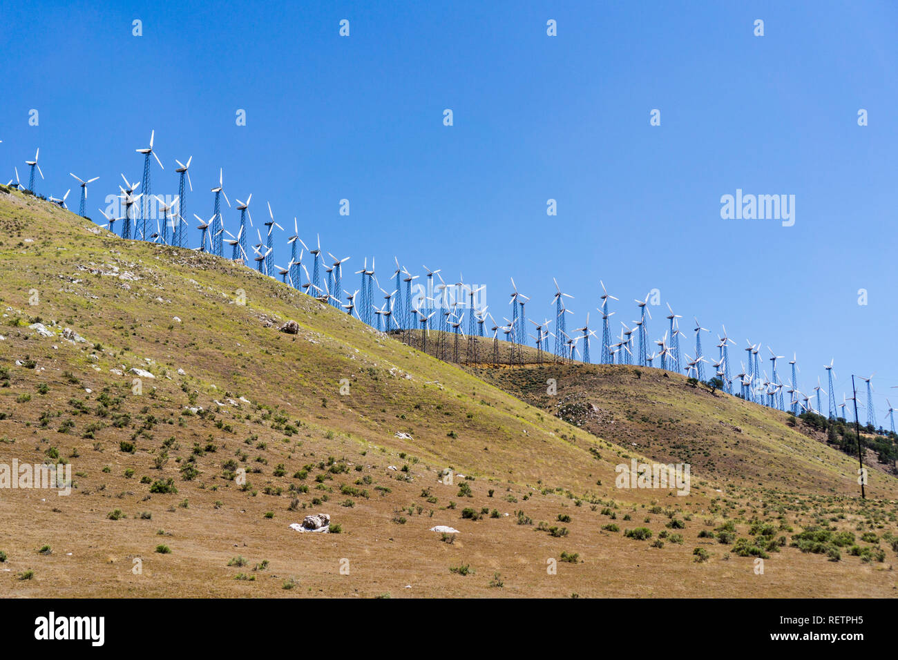 Many old and small Wind turbines on the top of golden hills in Kern county, south California Stock Photo