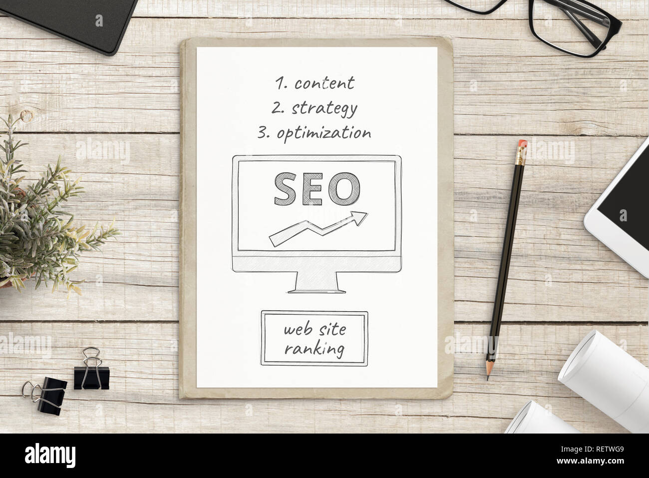 Search engine optimization sketch on white paper surrounded with office supplies. SEO web site concept. Stock Photo
