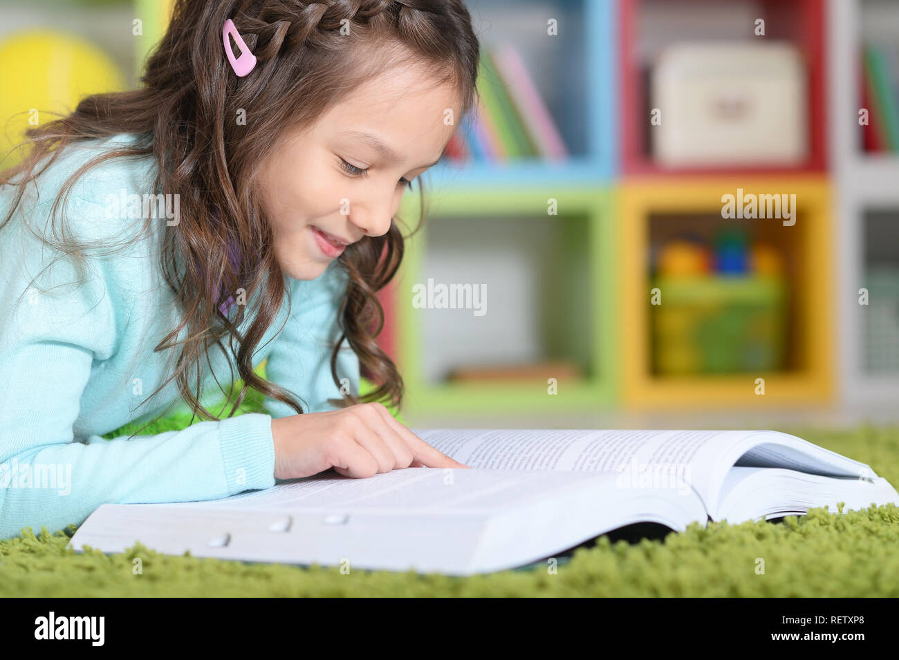 Portrait of little girl reading book at home Stock Photo - Alamy