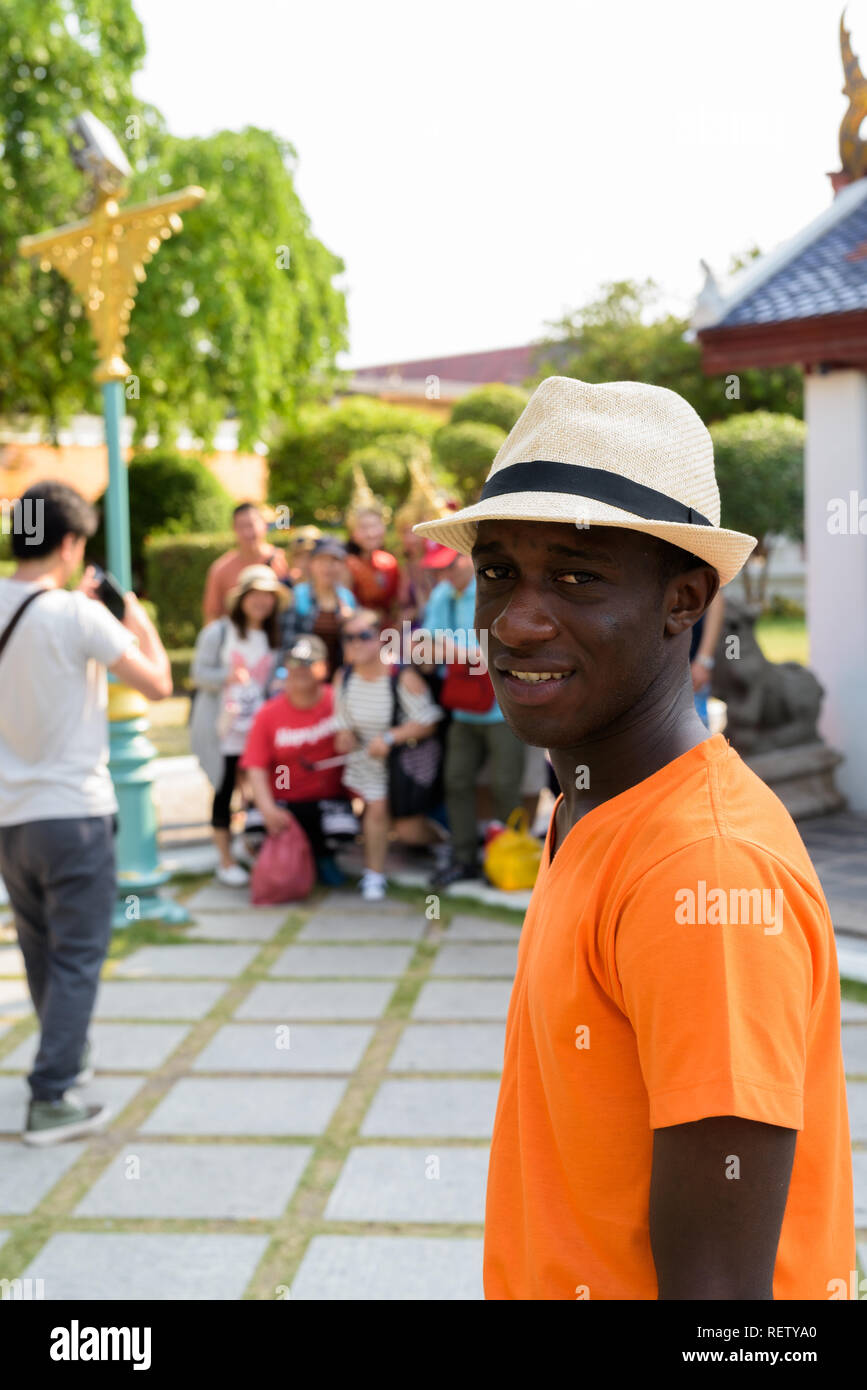 Young black African tourist man visiting Buddhist temple in Bangkok Stock Photo