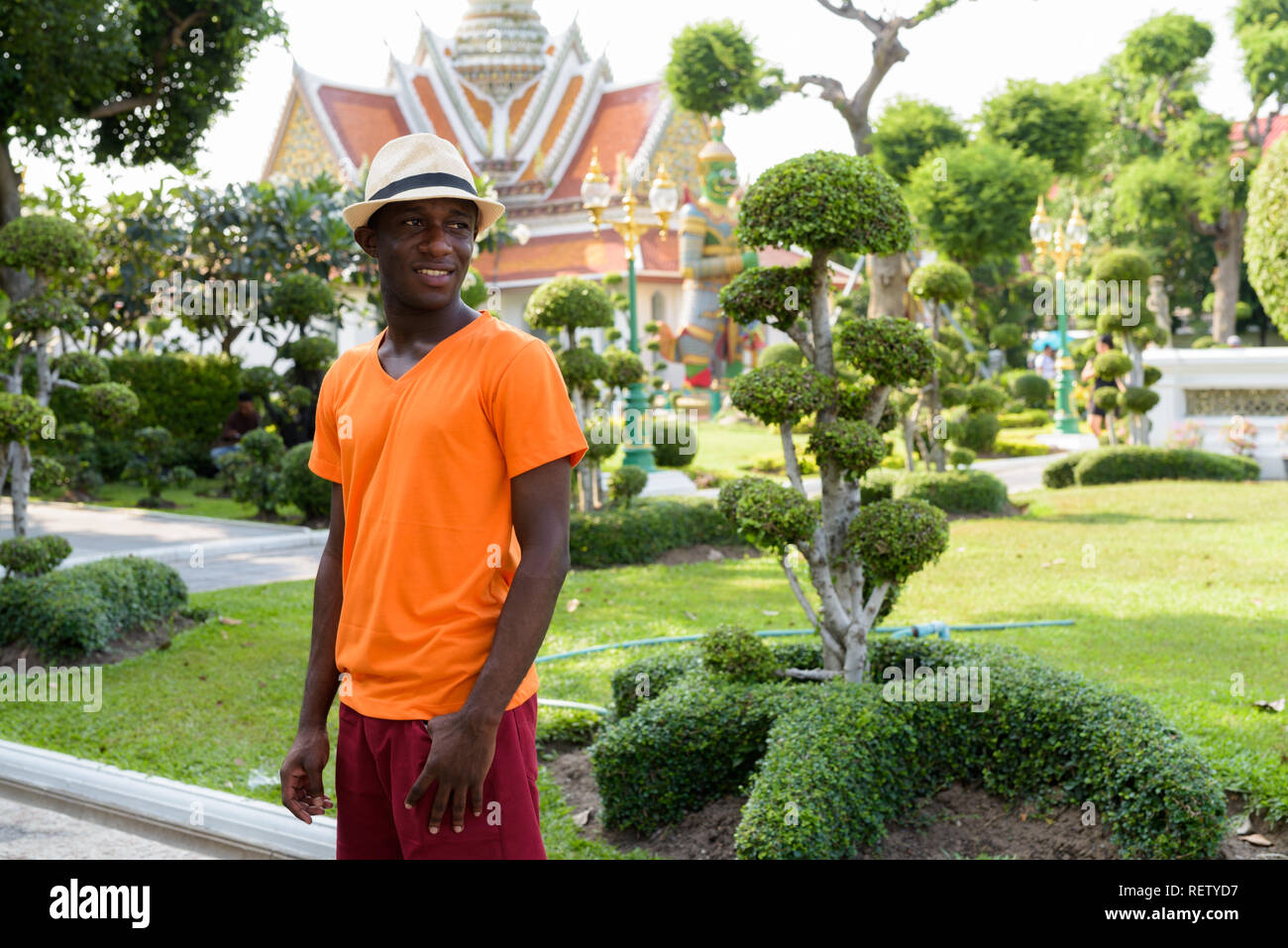 Young happy black African tourist man smiling at Wat Arun Stock Photo