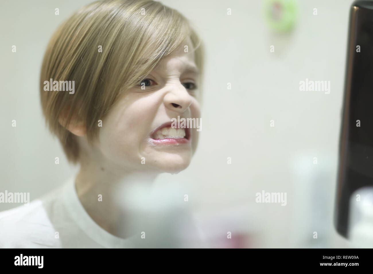 Boy Of School Age With A Stylish Haircut Examines Cleaned Teeth In