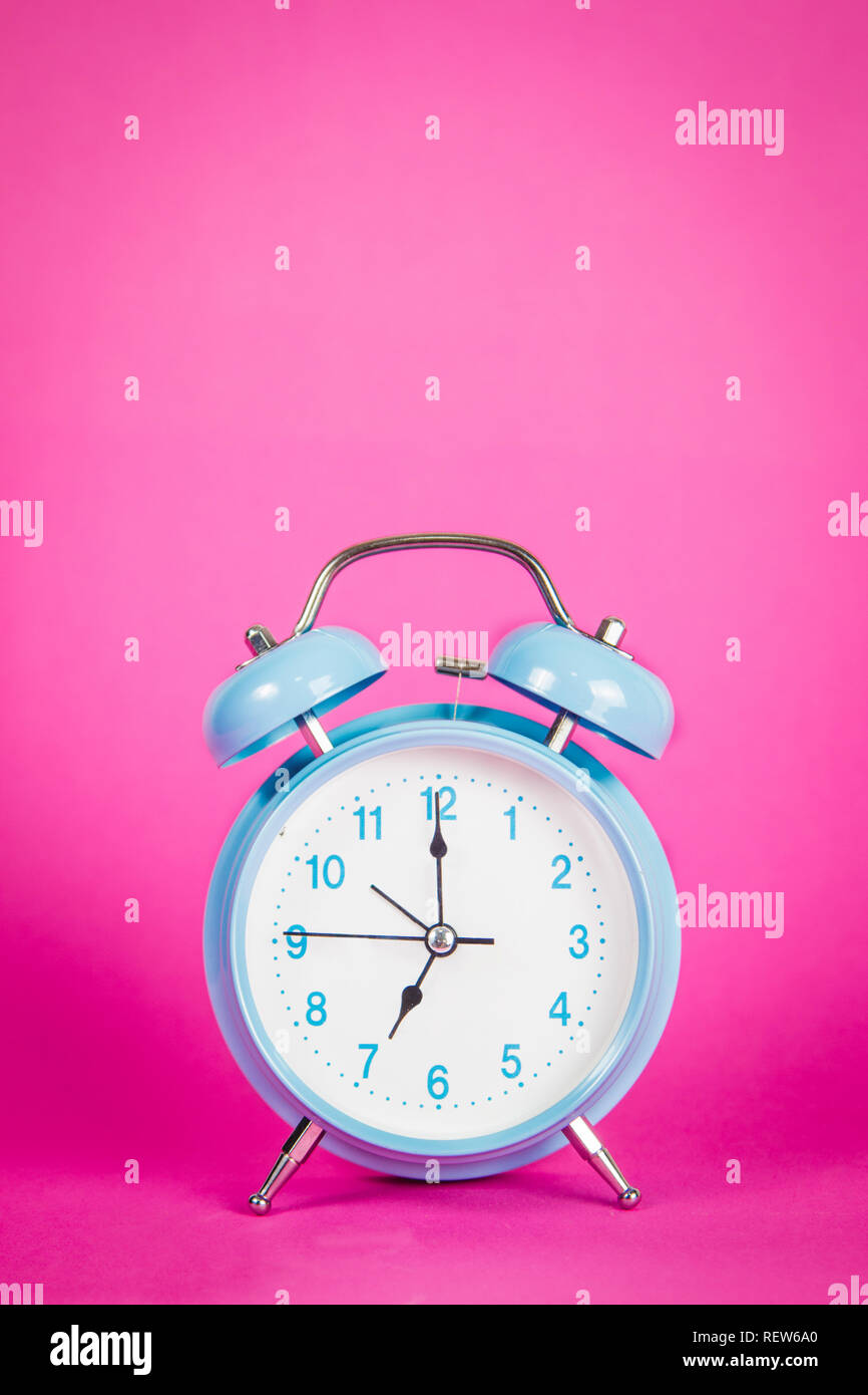 Beautiful retro blue pastel alarm clock on a vibrant pink background