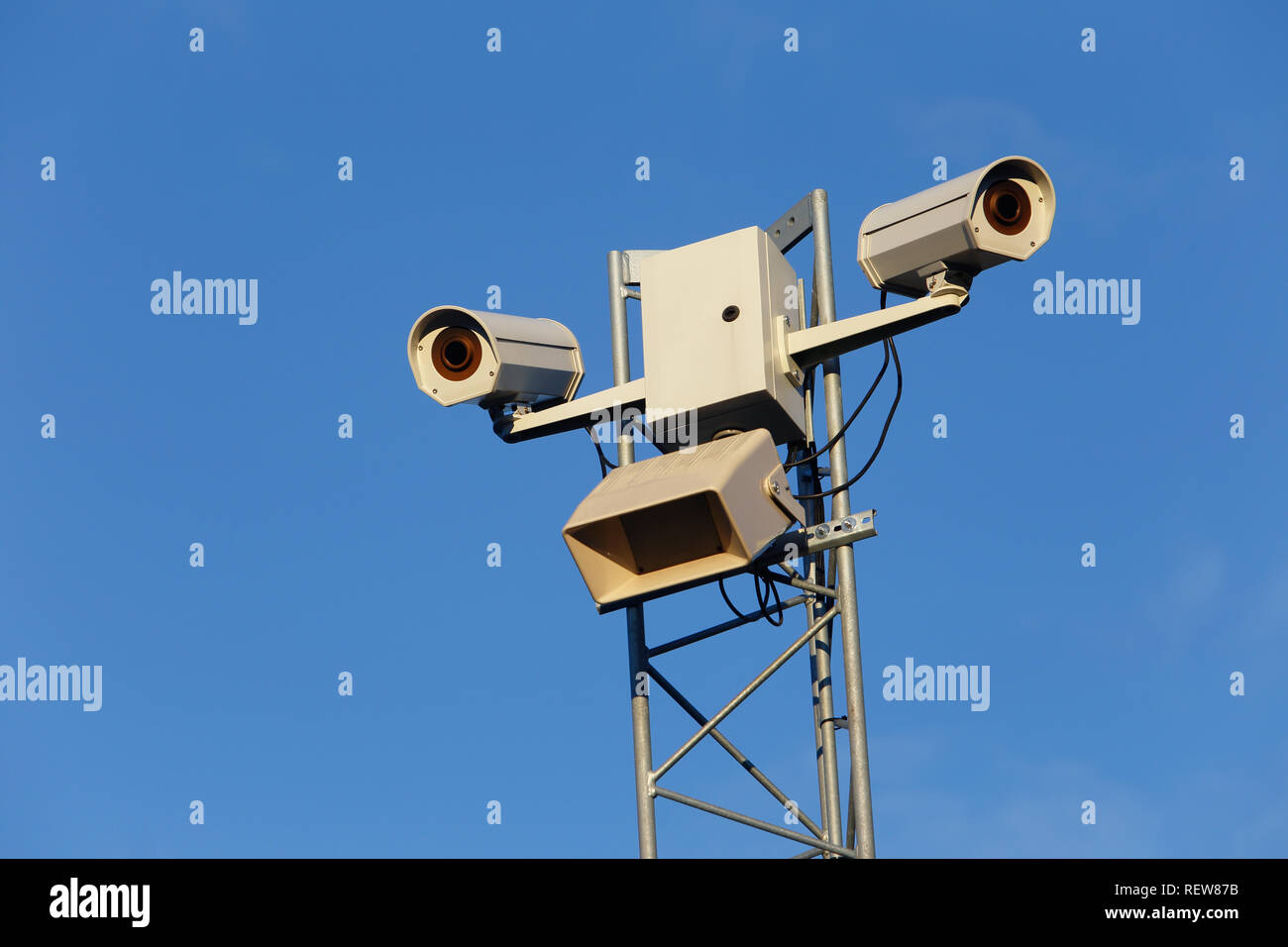 Low angel view of two outdoor surveillance cameras against a blue sky. Stock Photo